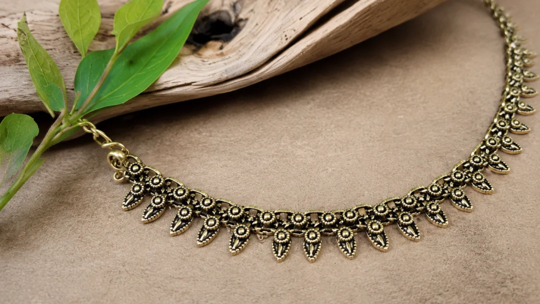 Collier en laiton dore pose sur du bois flotte